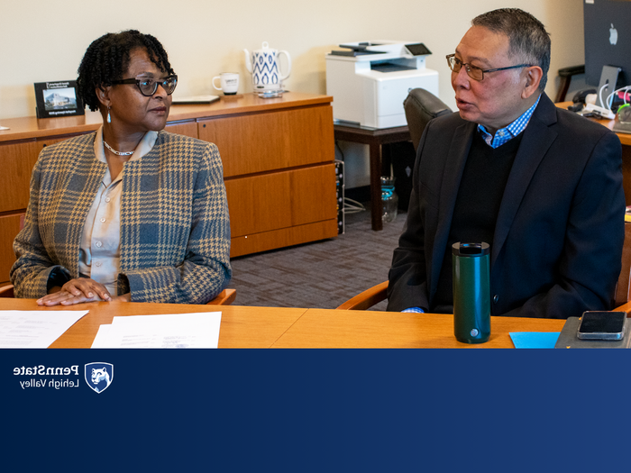 a male and female sit at a conference table speaking